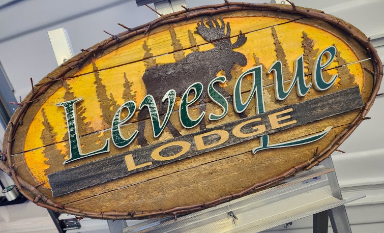 Handmade wooden sign for Levesque Lodge with routed sunset design and natural woodland frame.