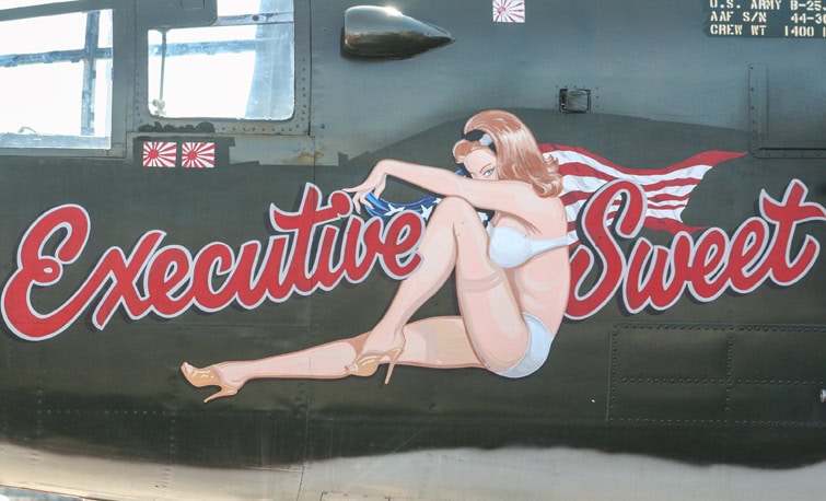 Hand-painted WWII-style nose art on B-25 Executive Sweet featuring a pin-up with American flag and bold lettering by J. Thow