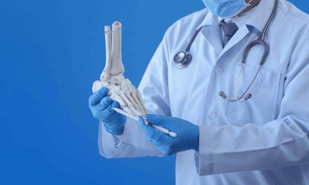 Anatomical model of a foot and ankle held by a doctor in medical gloves, representing orthopedic care at Kalyan Hospital.