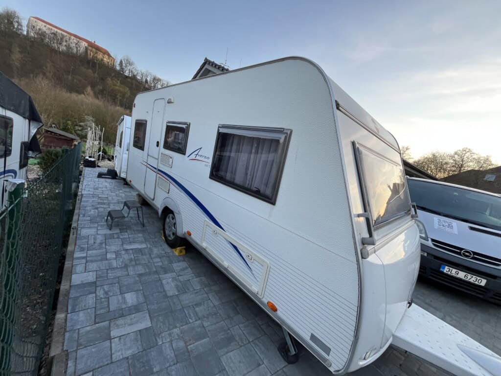 „Moderní rodinný karavan zaparkovaný v přírodě během letní dovolené – ideální pro cestování a kempování.“