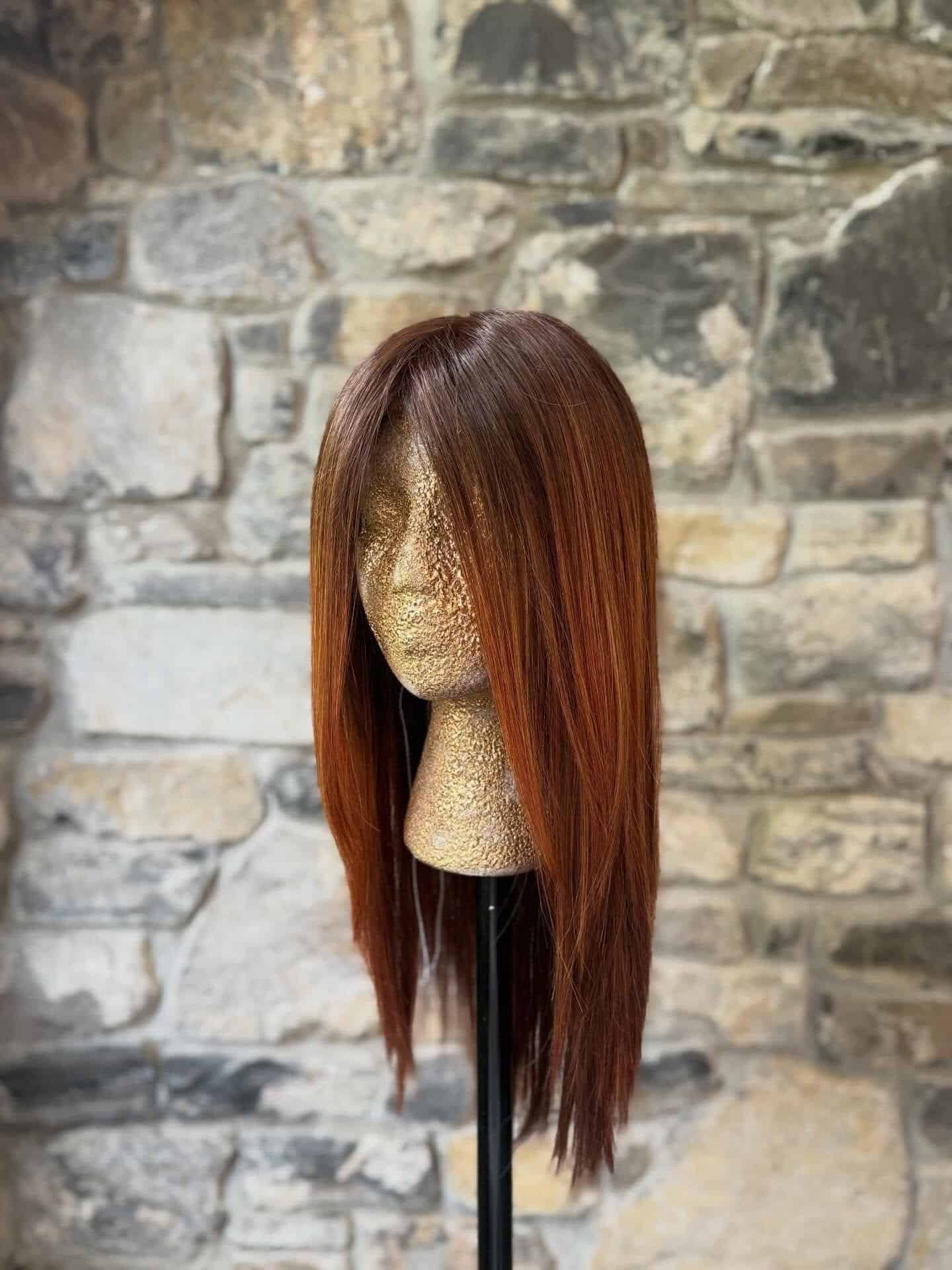 Long straight auburn hair wig on mannequin head for hair styling.