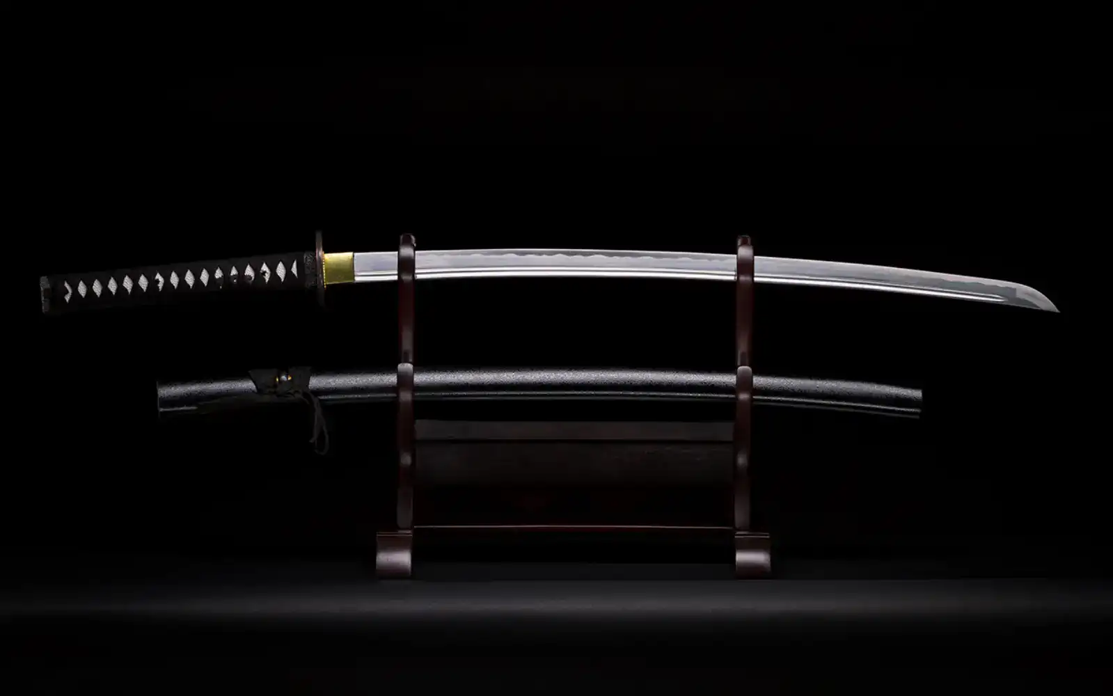 Japanese katana displayed on a wooden stand against a dark background