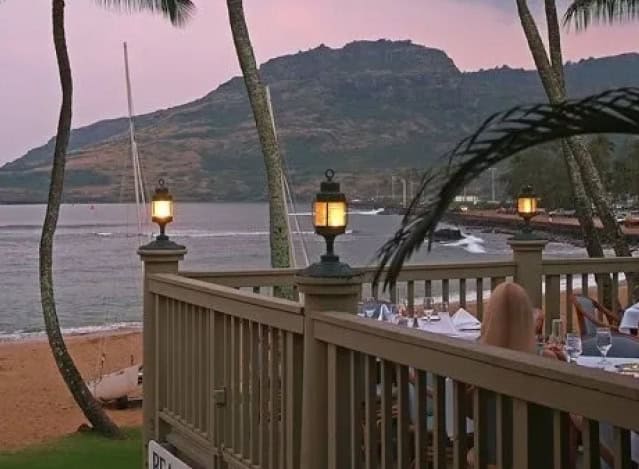A scenic view of the ocean from a restaurant deck, showcasing waves and distant boats under a clear blue sky.
