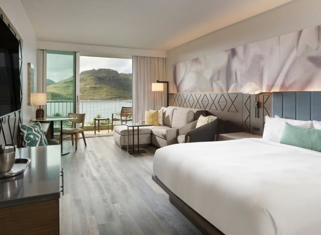A hotel room in Kauai, Hawaii, featuring a large bed and a television against a tropical-themed decor.