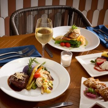 A dining table set with various plates of food and glasses of wine, creating an inviting atmosphere for a meal.