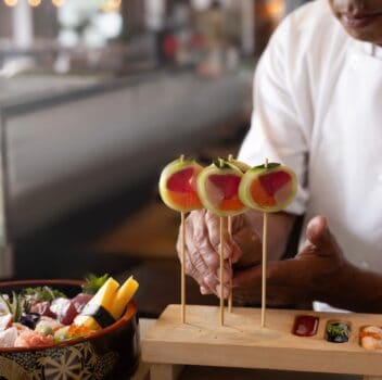 A chef skillfully prepares sushi on a wooden board, showcasing fresh ingredients and precise knife techniques.