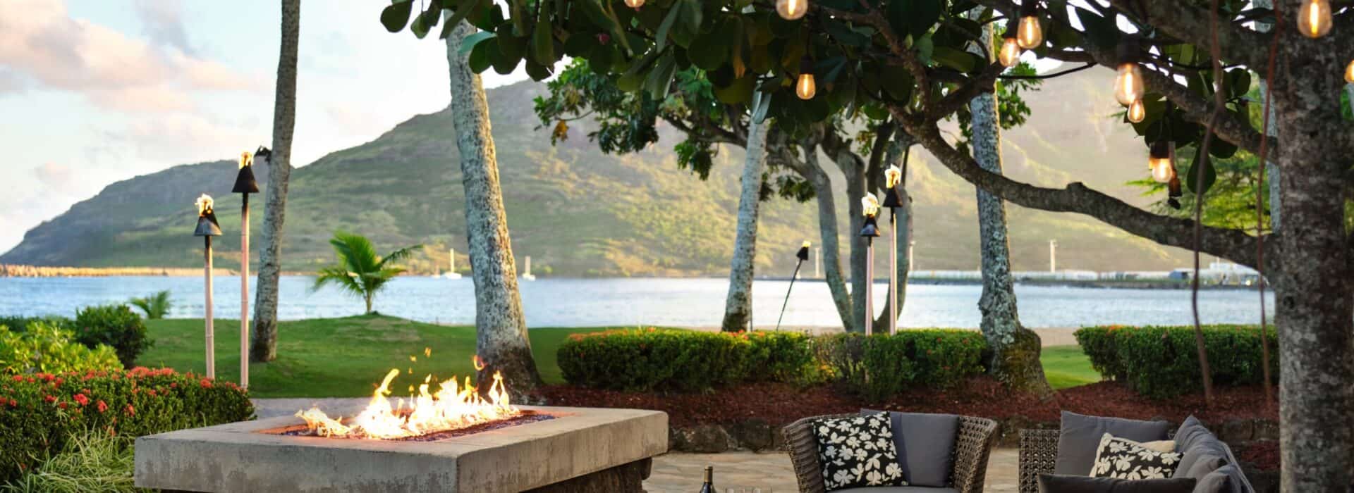 A cozy patio featuring a fire pit and chairs, overlooking a serene body of water.