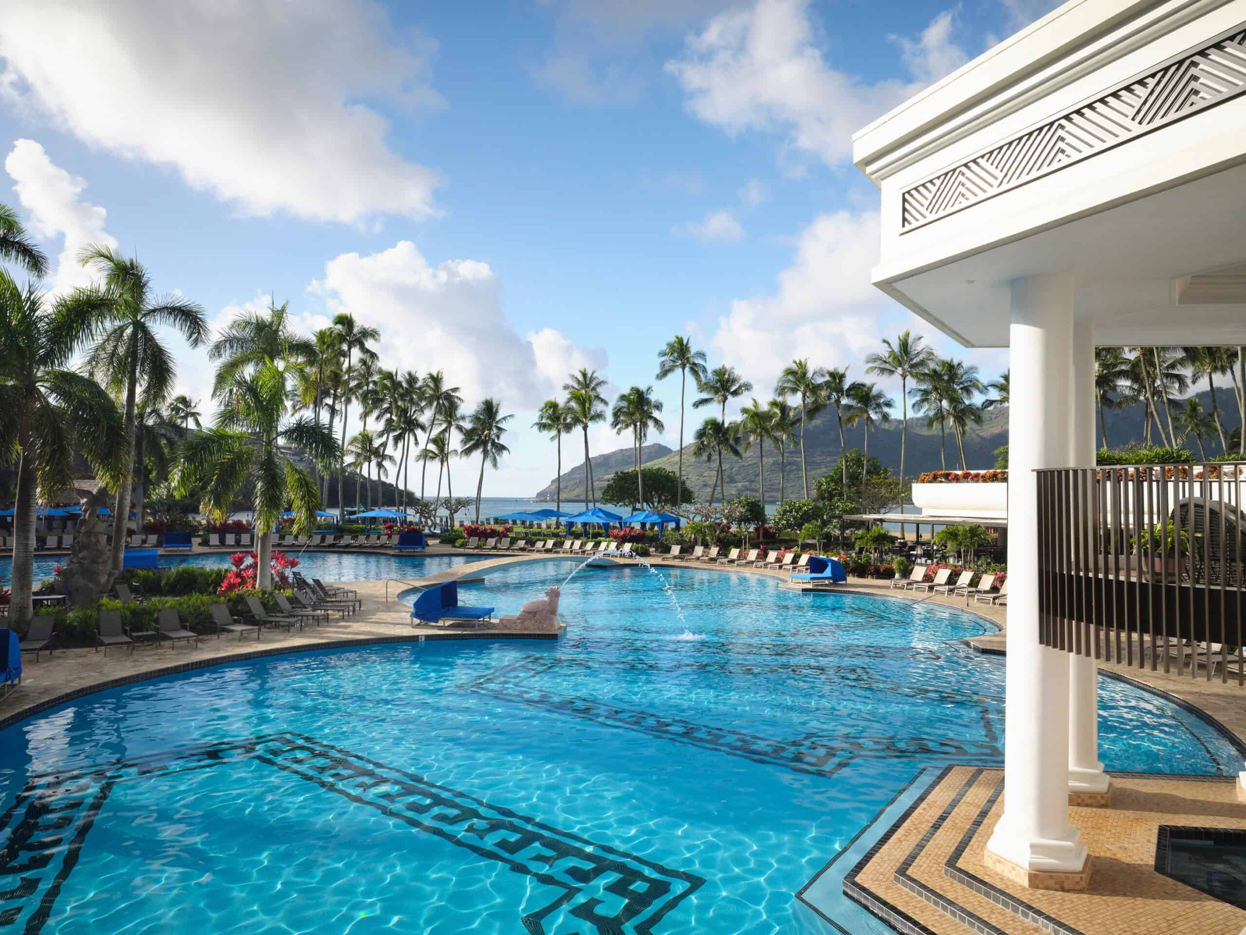 A resort pool in Kauai, Hawaii, featuring lounge chairs and umbrellas for relaxation under the sun.