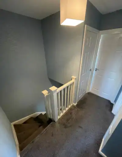 Hallway with staircase, painted walls, and white interior doors.