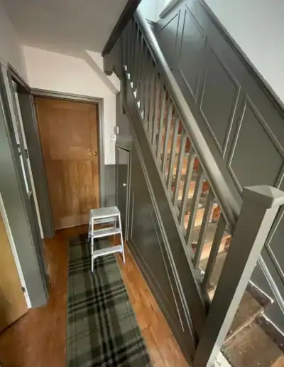Dark grey staircase with wooden steps and paneling, leading to the upper floor in a home interior.