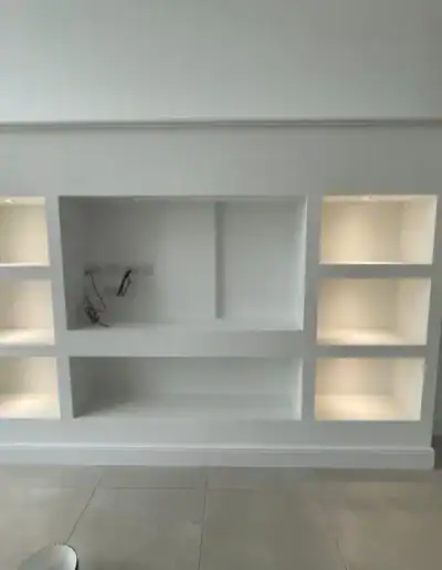Built-in white shelving unit for living room storage and display.