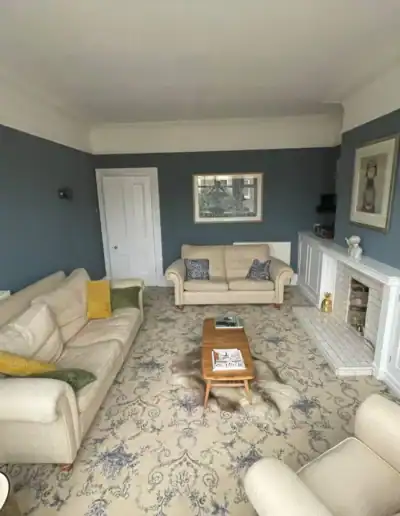Elegant living room with blue walls, white fireplace, and comfortable sofas.