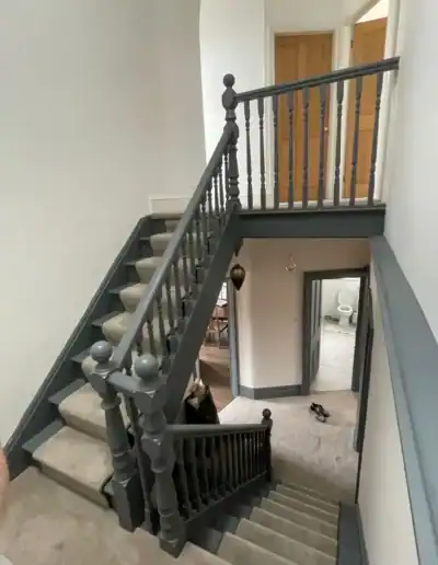 Elegant staircase renovation with grey handrails and beige carpeting.
