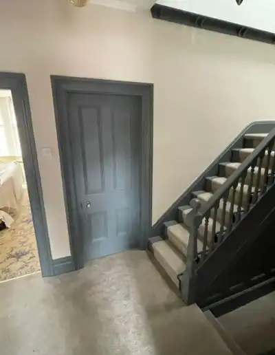 Staircase with dark wood banister and grey walls in a contemporary interior.