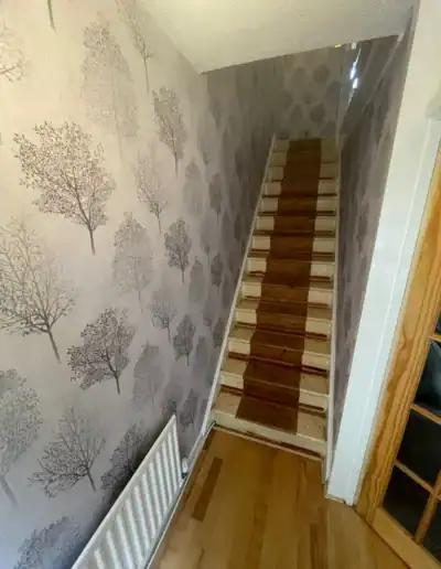 Wooden staircase with patterned wallpaper wall in a home interior.