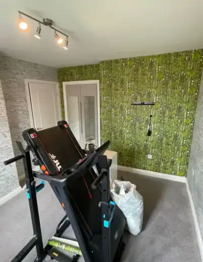 Home gym with treadmill and green wallpaper.