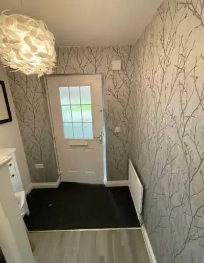 Modern hallway with tree-patterned wallpaper and white door, cozy interior decor.