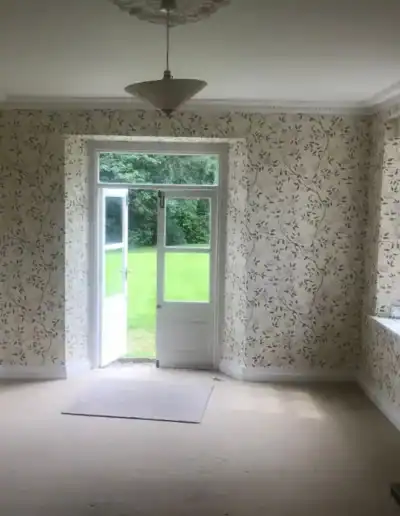 Stylish floral wallpaper decor in a spacious living room with large windows and a door to the garden.