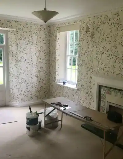 Elegant floral wallpaper in a bright living room with large windows and a fireplace.