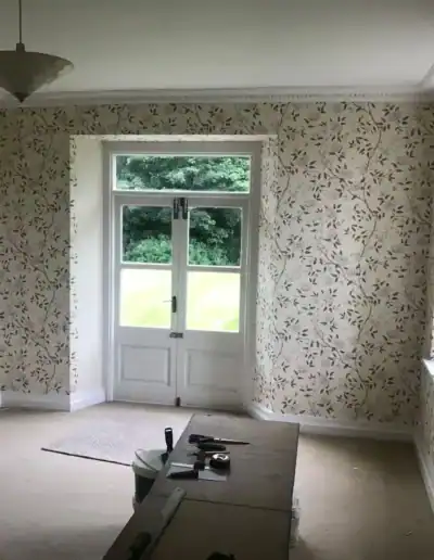 Elegant floral wallpapered living room with large window and minimal decor, ideal for a cozy, stylis.