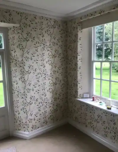 Decorative floral wallpaper in a bright living room with large windows and garden view.
