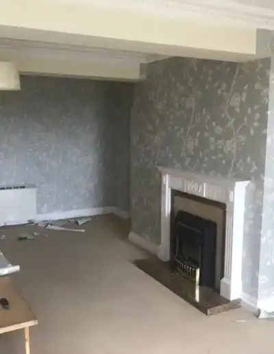 Living room with floral wallpaper, fireplace, and neutral decor for a cozy atmosphere.