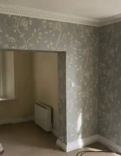 Decorative floral wallpaper on living room walls with large window and natural light.