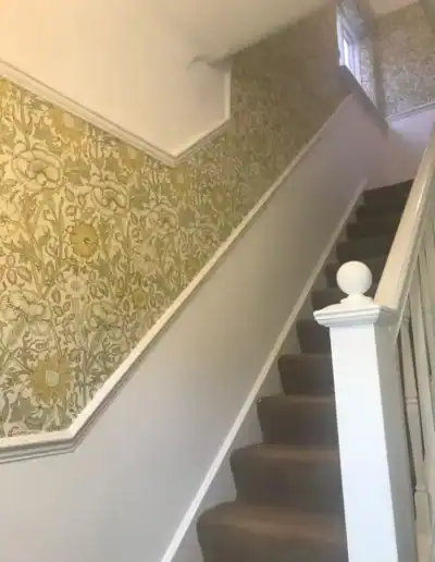 Interior staircase with floral wallpaper and white banister, modern home decor.