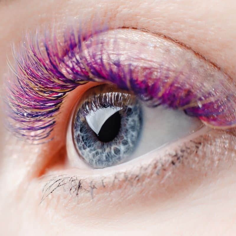 Nahaufnahme eines blauen Auges mit violett-pinker Wimpernverlängerung im Nagelstudio K Beauty in Berlin