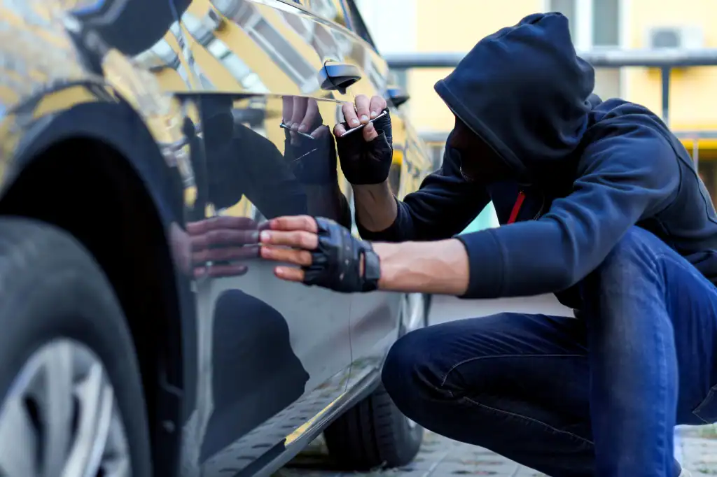 Burglary suspect vandalizing a car during a crime scene, law enforcement investigation, or theft, with focus on criminal activity and legal cases.