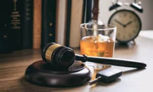 Gavel on a legal desk with a glass of whiskey, car keys, and an alarm clock, symbolizing legal defense, crime, and time-sensitive legal issues. Suitable for criminal law, legal cases, and attorney services.