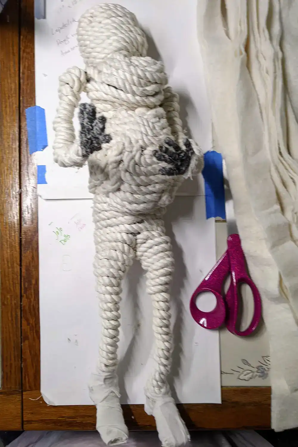 Ella the forest spirit art doll during the cord wrapping process, showing her body being fleshed out with bulky cord before adding batting and yarn.