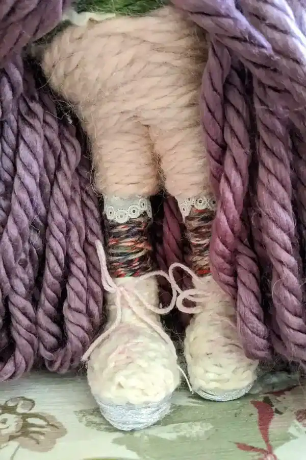 Close-up of Leela the health and wellness art doll’s pink and white tennis shoes, paired with pink "spandex" half leggings beneath her purple skirt.