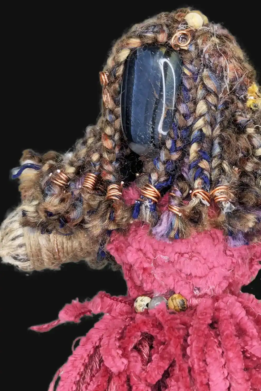 Close-up of Absynthe Healing Art Doll showcasing her Blue Tiger’s Eye gemstone head, braided multicolored yarn hair with copper wire accents, set against a black background.