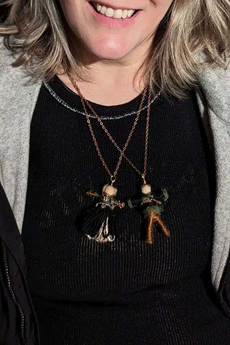 A couple of very small dolls worn as a pendant on a necklace.