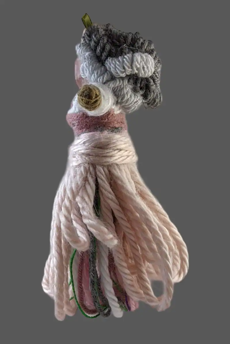 The side view of the "grandma" You-do-You Voodoo™ art doll with her curly salt and pepper hair.