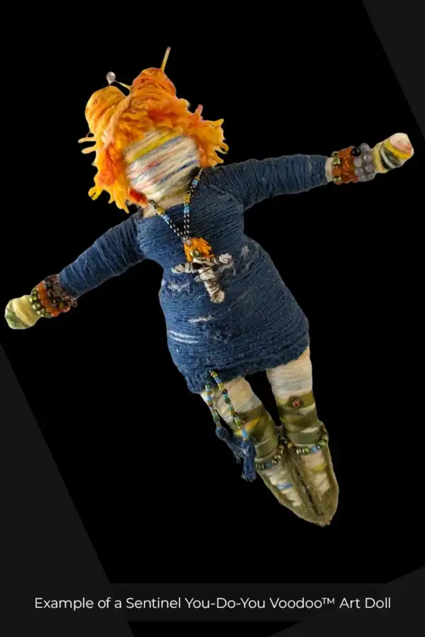 Image of "Butterfly", a You-Do-You Voodoo™ art doll that represents the Sentinel line of art dolls. Her hair is orangish, she wears a blue dress, green ballet flats, jewelry, pencils in her hair to hold it into buns, and a mini voodoo doll on a chain around her neck.