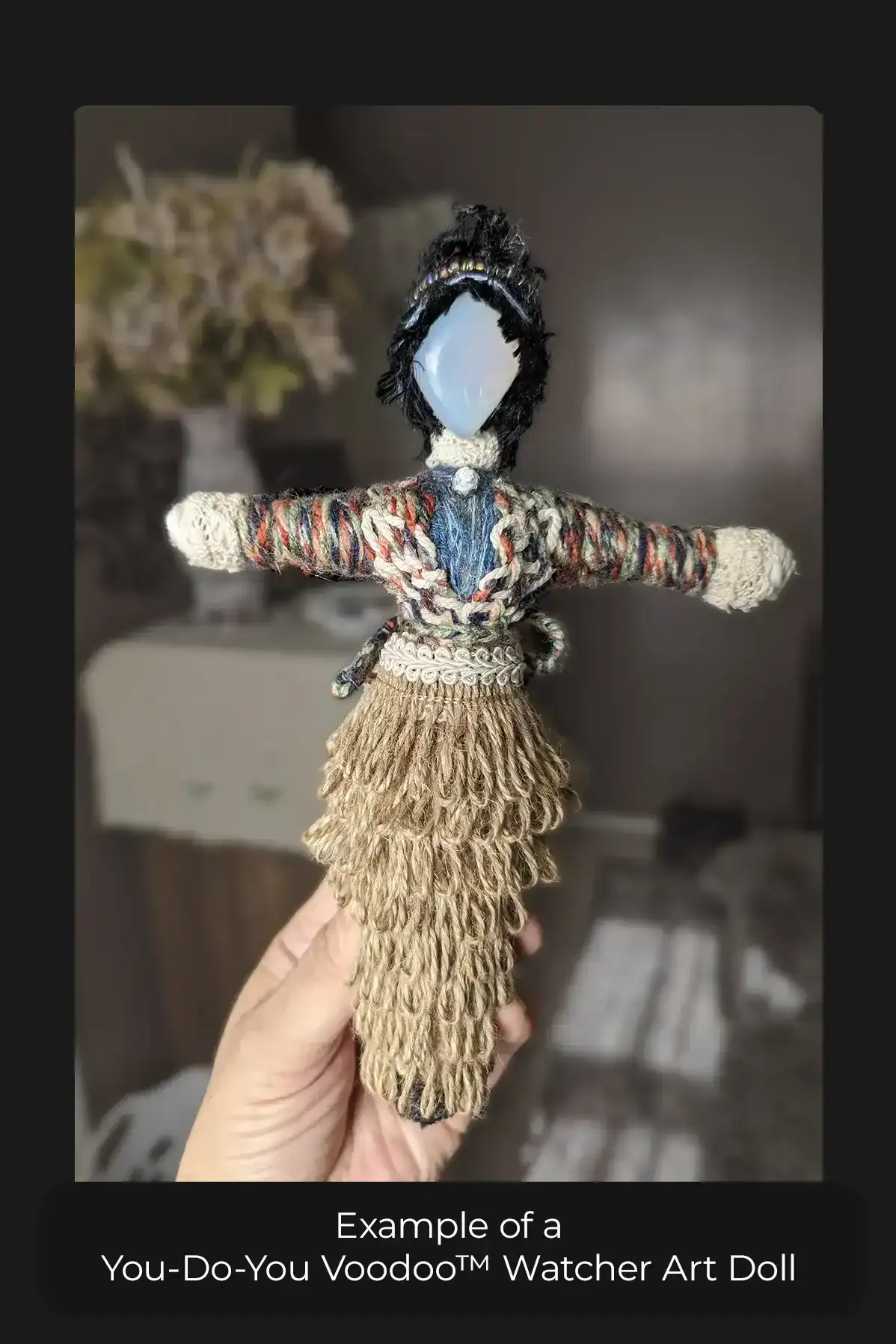 Example of a You-Do-You Voodoo™ Watcher doll held in a woman's hand. She has a black messy bun, colorful double-layered top and a jute ribbon skirt.