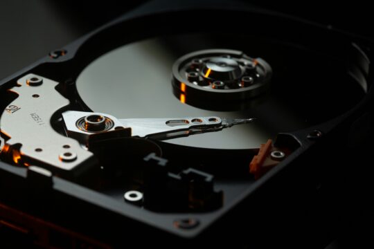 High-resolution image of computer hard drive, showcasing storage device with spinning disk and actuator arm.