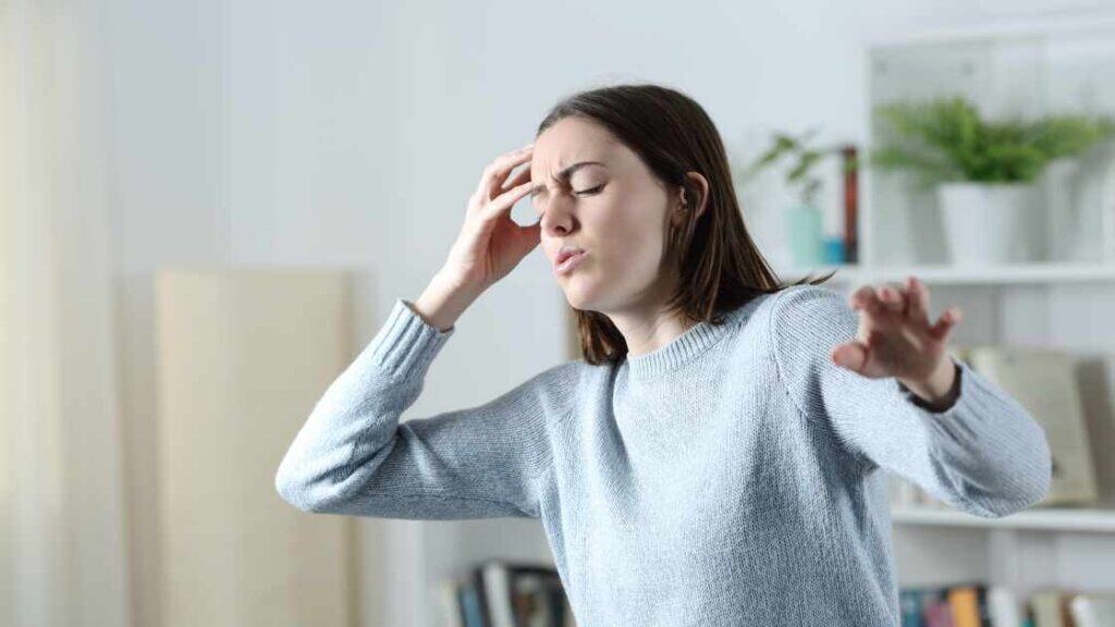 Teen girl with hand on head appearing dizzy or overwhelmed, representing emotional and physical signs of teen depression.