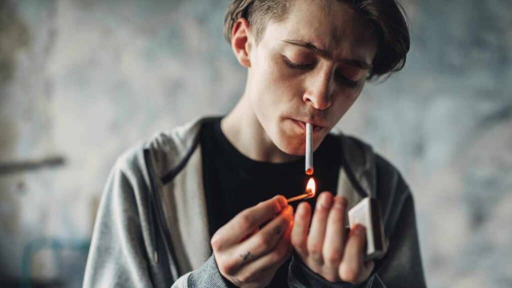 Teen boy lighting a cigarette, representing substance use as an overlooked and emerging cause of teen depression.