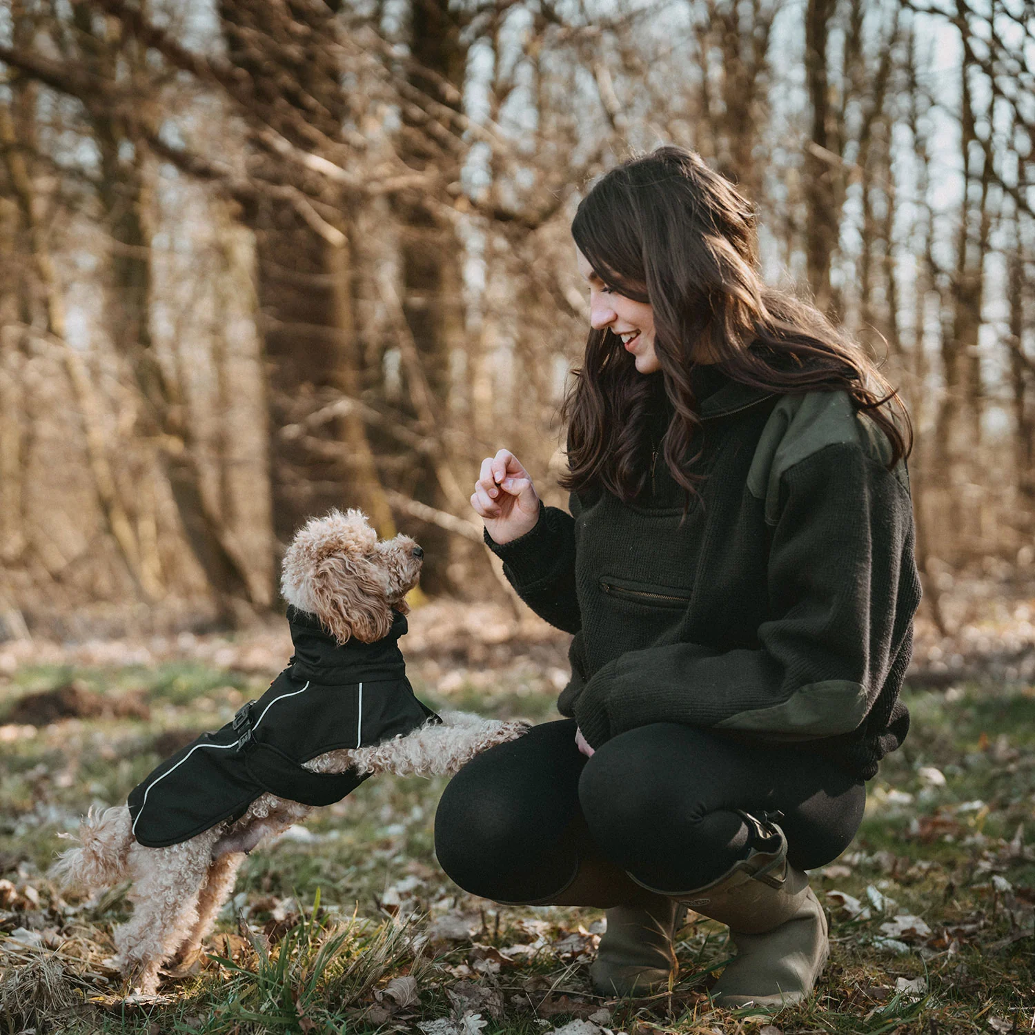 Fröhliche Frau mit Pudel im Wald, spielende Hunde, Hundezubehör, Vierbeiner, Natur, Hundetraining, Hundesport, Hundeshop, Outdoor-Aktivitäten mit Hund, Hundeleben, Tierliebe, Hundespielzeug, Hundebekleidung, Hundefreundschaft, Kiezhund Hundeshop, Kauf von Hundezubehör online.