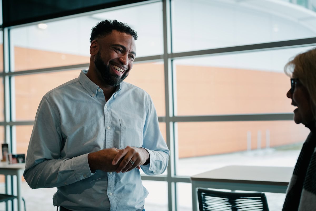 A smiling man in a light blue shirt engaging in a friendly discussion with a woman in an office