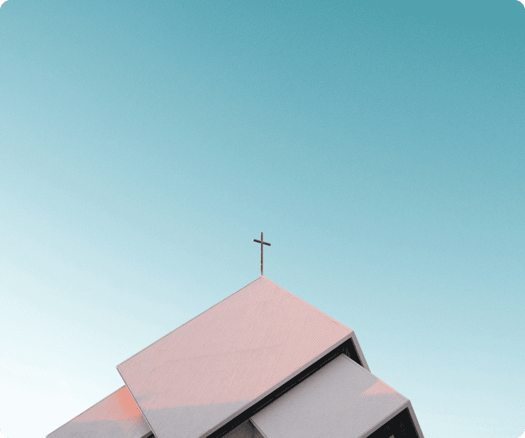 Modern church building with a cross on the roof against a bright blue sky.