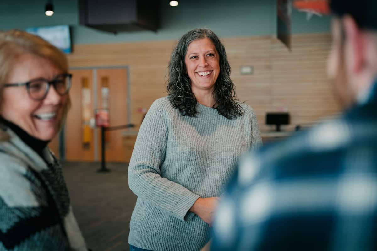 Women smiling and engaging in conversation in a modern, well-lit space
