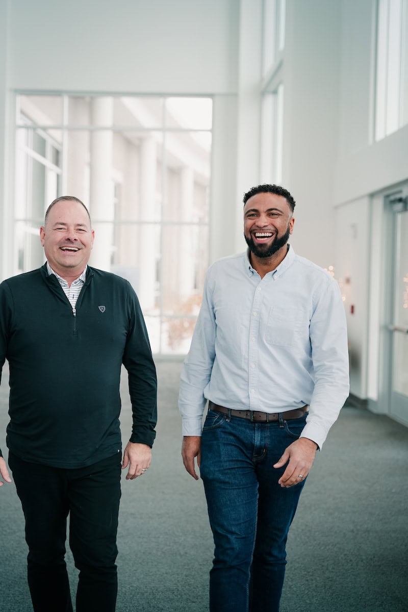 Two smiling men walking down a hall at a bank