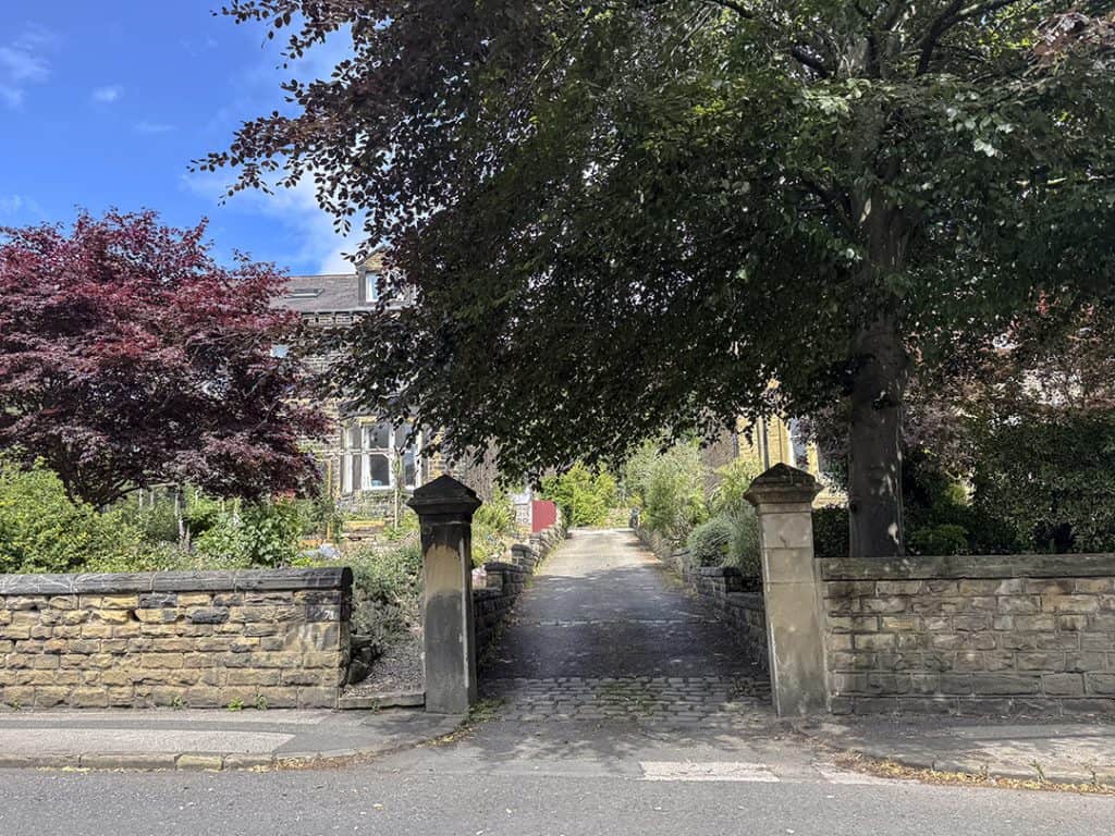 Exterior of 76 and 78 Morris Lane, Victorian stone houses, with a steep tarmac and cobblestone driveway leading up between them.