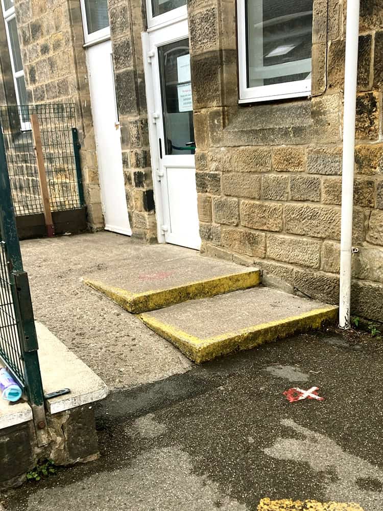 The entrance to St Stephen's Primary School. There are steps and a ramp to the entrance. The door is white.