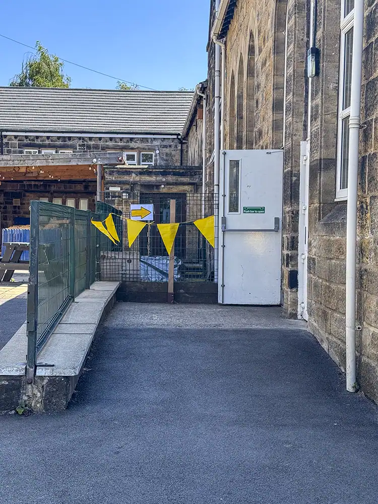 The ramp leading to a side door, with yellow bunting and a directional arrow sign.