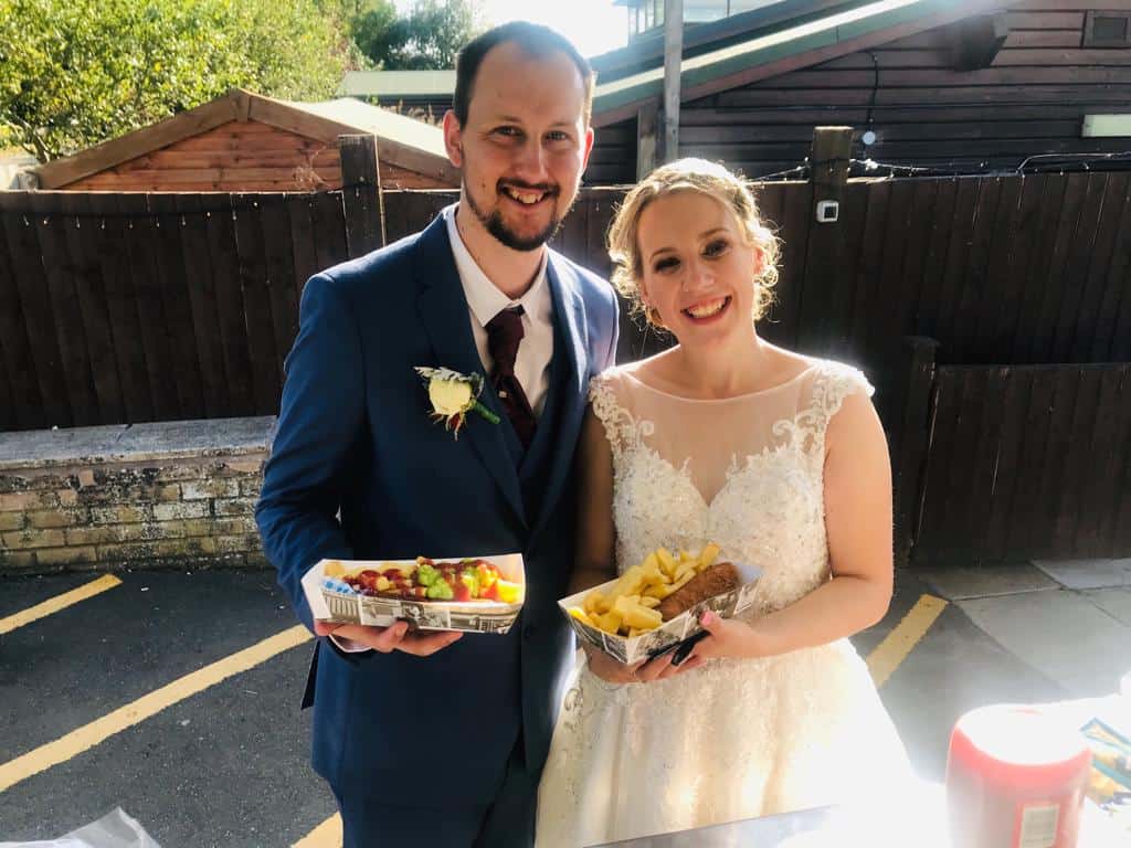 Wedding couple smiling with fish and chips served from KK Catering's wedding fish and chip van.